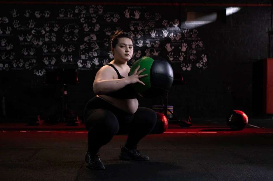 Uśmiechnięta osoba w stroju sportowym trzymająca piłkę.